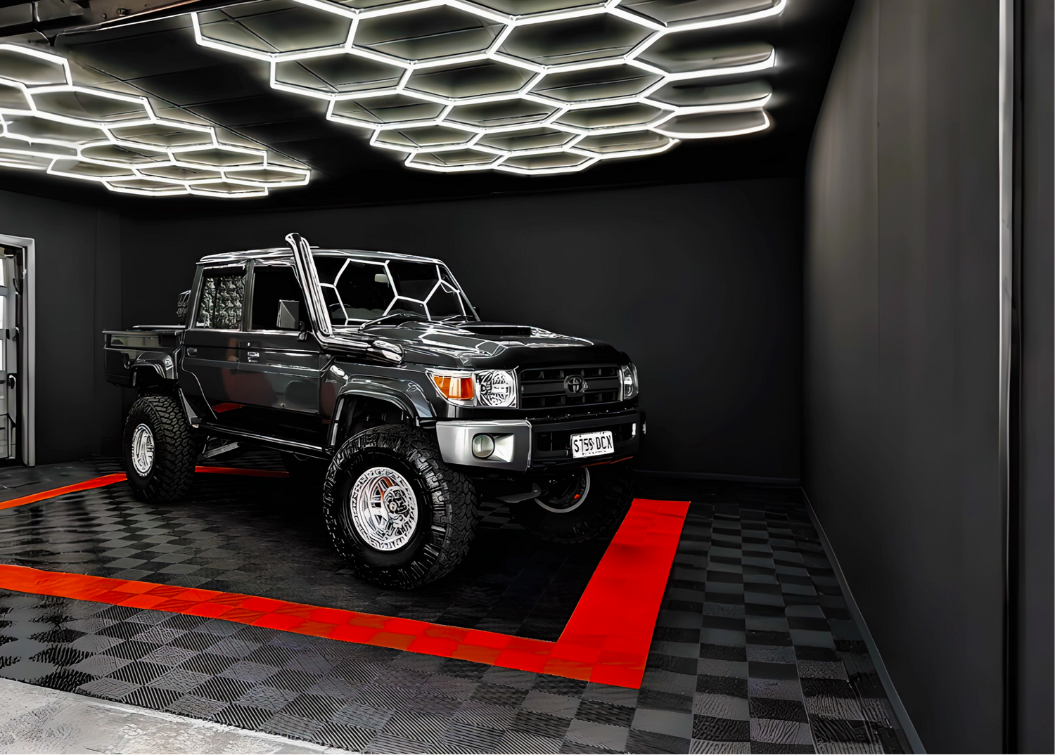 Black truck inside a modern garage with geometric ceiling lights